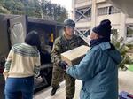 　石川県珠洲市立緑丘中で、震災後初めて陸上自衛隊の隊員から物資を受け取る避難者ら＝２月５日午前