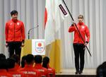 　杭州アジア大会の日本選手団結団式で、尾県貢団長（左）から団旗を受け取ったフェンシング女子の江村美咲＝１５日午後、東京都内のホテル
