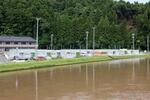 　石川県穴水町の「川島第３団地」。後方の山に崩れた跡があり、川は大雨で増水していた＝７月２４日