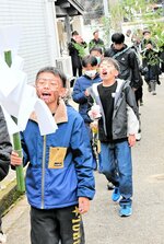 顔に墨を塗り約１㌔先の祠まで地区内を練り歩く一行＝５日、香美町香住区沖浦