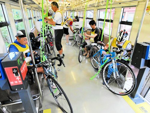 自転車を列車内に積み込み安全ベルトで固定するサイクリストら＝１９日、ＪＲ泊駅