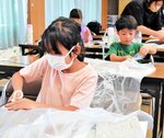 ごみ袋を使って応急用の雨具ポンチョを作る子どもたち