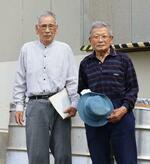 　神島発電所の前に立つ小久保知明さん（左）と藤原喜代造さん＝２０２４年５月、三重県鳥羽市