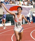 １９９１年９月、陸上世界選手権の男子マラソンで日本に初の金メダルをもたらし、日の丸の旗を掲げて観客の声援にこたえる谷口浩美さん＝国立競技場