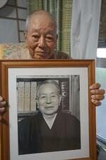 　故牧野清さんの写真を手にする長男の光博さん＝２０２３年６月、沖縄県石垣市