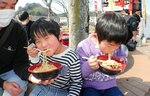 地元店舗のラーメンをおいしそうに頰張る子ども＝１６日、米子市末広町の米子コンベンションセンター特設会場