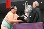 大相撲九州場所で初優勝を果たし、日本相撲協会の八角理事長（右）から賜杯を受け取る琴桜＝２４日、福岡市の福岡国際センター（代表撮影）