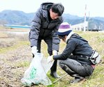 ごみ袋片手に岸田川河川敷に散らばったごみを拾い集める参加者＝１５日、新温泉町浜坂の岸田川