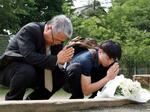 　松本サリン事件で犠牲者が出た寮跡地の公園で、献花し手を合わせる映画監督のさかはらあつしさん（左）ら＝２５日午後、長野県松本市