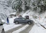 　雪が積もり凍結した石川県穴水町の道路で、Ｕターンする車＝１４日午前