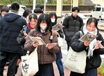 カイロなどを手に試験会場へ向かう受験生＝１８日、鳥取市の鳥取大前