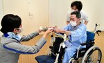 ＡＮＡ客室乗務員の溝口さん（左）からスズランを受け取る入院患者ら＝２１日、鳥取市の鳥取赤十字病院