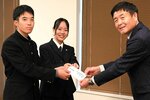 乾総務部長（右）に目録を手渡す尾崎さん（左）と上嶋さん＝２４日、鳥取市役所