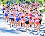 日本海駅伝　スタートした競技場から勢いよくロードへと駆けだす１区の走者ら＝１３日、鳥取県倉吉市