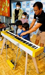 寄贈された電子ピアノの音色を楽しむ家族連れ＝１２日、鳥取市の鳥取砂丘コナン空港