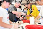 地元の民宿経営者などに白イカのさばき方を教わる参加者たち＝１６日、香美町香住区訓谷の月見草