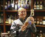 　海洋熟成したウイスキーを紹介する「北海道海洋熟成」代表取締役の本間一慶さん＝札幌市の繁華街ススキノ（２０２４年６月）