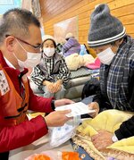 避難所で調剤した薬を手渡して容体について話しかける大村さん（左）＝２１日、石川県穴水町内の避難所（本人提供）