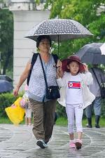 　平壌市内を傘を差して歩く市民＝２８日（共同）