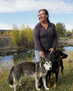 　アトリエを兼ねた自宅の庭で愛犬と笑顔を見せるジャッキー・オルソン。「私たち先住民は互いに助け合って生きている」と語る＝２０２４年９月、カナダ・ドーソン（撮影・大塚圭一郎、共同）