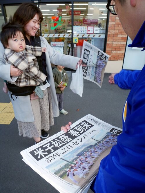 号外を受け取る親子連れ＝２４日、ＪＲ米子駅前