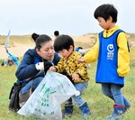 草むらに埋もれたごみを協力して拾い集める親子連れ＝８日、鳥取市の鳥取砂丘