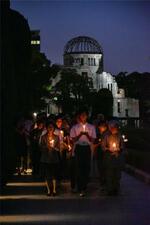 　「ヒロシマ平和の灯のつどい」で、ろうそくを手に歩く人たち。後方は原爆ドーム＝３１日夕、広島市の平和記念公園