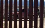 　「国境の壁」のメキシコ側に到着した車。黒いフードを深くかぶる男は、闇業者「コヨーテ」だ＝１月２３日、米ハクンバホットスプリングス（共同）