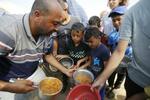 　２４日、パレスチナ自治区ガザ南部ハンユニスの難民キャンプで国連の担当者から食事を受け取る子どもら（ゲッティ＝共同）