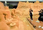 砂の彫刻を写真に収めるツアー客