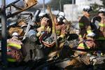 　一帯が火災で焼失した「輪島朝市」付近で捜索活動を行う消防隊員ら＝１７日午後、石川県輪島市