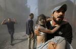 　イスラエル軍の空爆で負傷した子どもを運ぶパレスチナ人男性＝２６日、ガザ地区南部ハンユニス（ロイター＝共同）