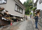　１月の地震で全壊判定になり、３日朝の震度５強の揺れで１階部分がつぶれた自宅を見つめる中谷博之さん＝３日午後、石川県輪島市