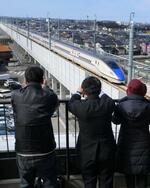 　「トレインパーク白山」の屋上展望デッキから、試験走行する北陸新幹線を見る人たち＝１３日午前、石川県白山市