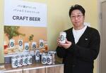 　パンの耳を使ったクラフトビールの商品を手にする栄屋製パンの吉岡謙一専務＝１月、神奈川県海老名市