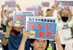 　ボードを掲げ、現行保険証の廃止反対を訴える人たち＝６月、福岡市