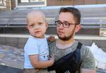 　ロシアのミサイル攻撃で破壊されたウクライナ・キーウの小児病院を訪れたオレクサンドルさん（右）と長男ルドビクちゃん。ルドビクちゃんは血液のがんを患っている＝９日（共同）