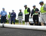 水を吸い上げて膨らんだホースを確認する参加者ら＝３０日、鳥取市浜坂の袋川