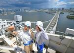 　開通３０周年を迎えたレインボーブリッジの主塔の上で記念撮影する参加者＝２６日午前、東京都港区