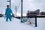 　石川県羽咋市で降り積もった雪の中を犬と散歩する住民＝２１日夕