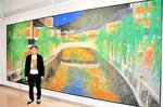 北但大震災から来年で１００年を迎える城崎温泉街の今を描いた作品と山田さん＝豊岡市小島の県立円山川公苑美術館