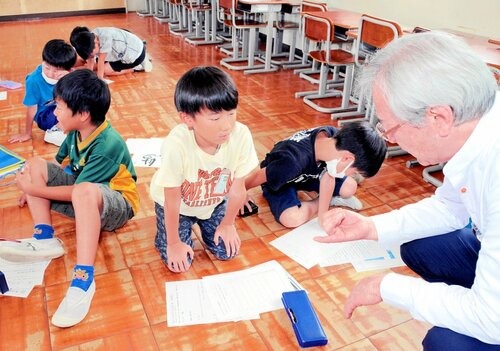 押本さん（右）の指導で短歌作りを楽しむ児童ら＝８日、鳥取市国府町宮下の宮ノ下小