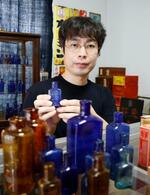 　大正から昭和にかけて使われていたガラス製の薬瓶を集めている丸藤裕貴さん＝２０２４年９月、富山市