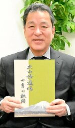 「大山悟道場十年の軌跡」を手にする松原事務局長