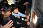 　まきストーブで手を温める神戸市立六甲山小の児童ら＝２４日午前