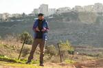 　ベイトイクサで１月２１日、イスラエルへの怒りを訴えるアフマドさん。背後にはイスラエルの居住エリアが広がる（共同）