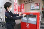 　郵便ポストに年賀状用のラベルを貼る郵便局員＝１４日午後、東京都千代田区の麹町郵便局