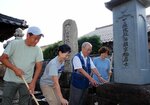 横田内膳の墓石を掃除する道正さん（右から２人目）と日の出湯元気ふろジェクトのメンバー＝５日、米子市寺町の妙興寺