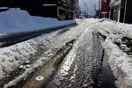 　雪解け水に覆われた、石川県珠洲市の市道の消雪装置（手前）＝６日午後