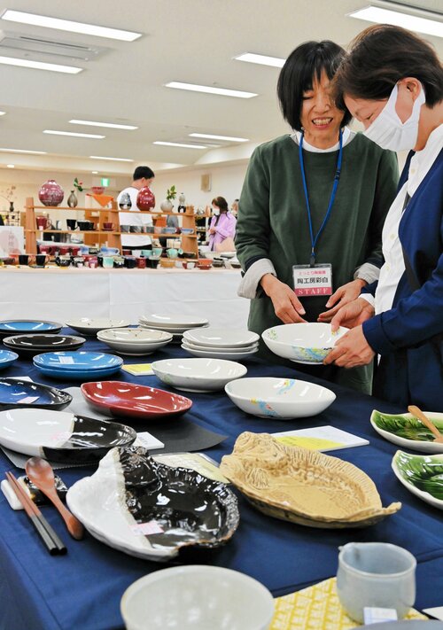 カレー皿を手にとり窯元との会話を楽しむ来場者＝２０日、鳥取市富安２丁目の日本海新聞ビル５階ホール